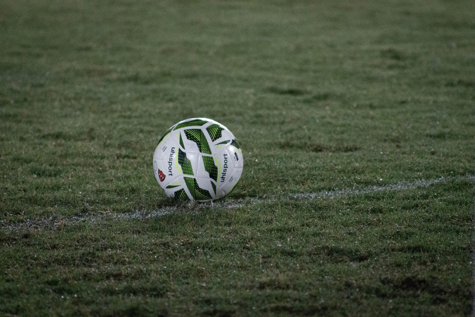 A hand pump with a pressure gauge beside a soccer ball