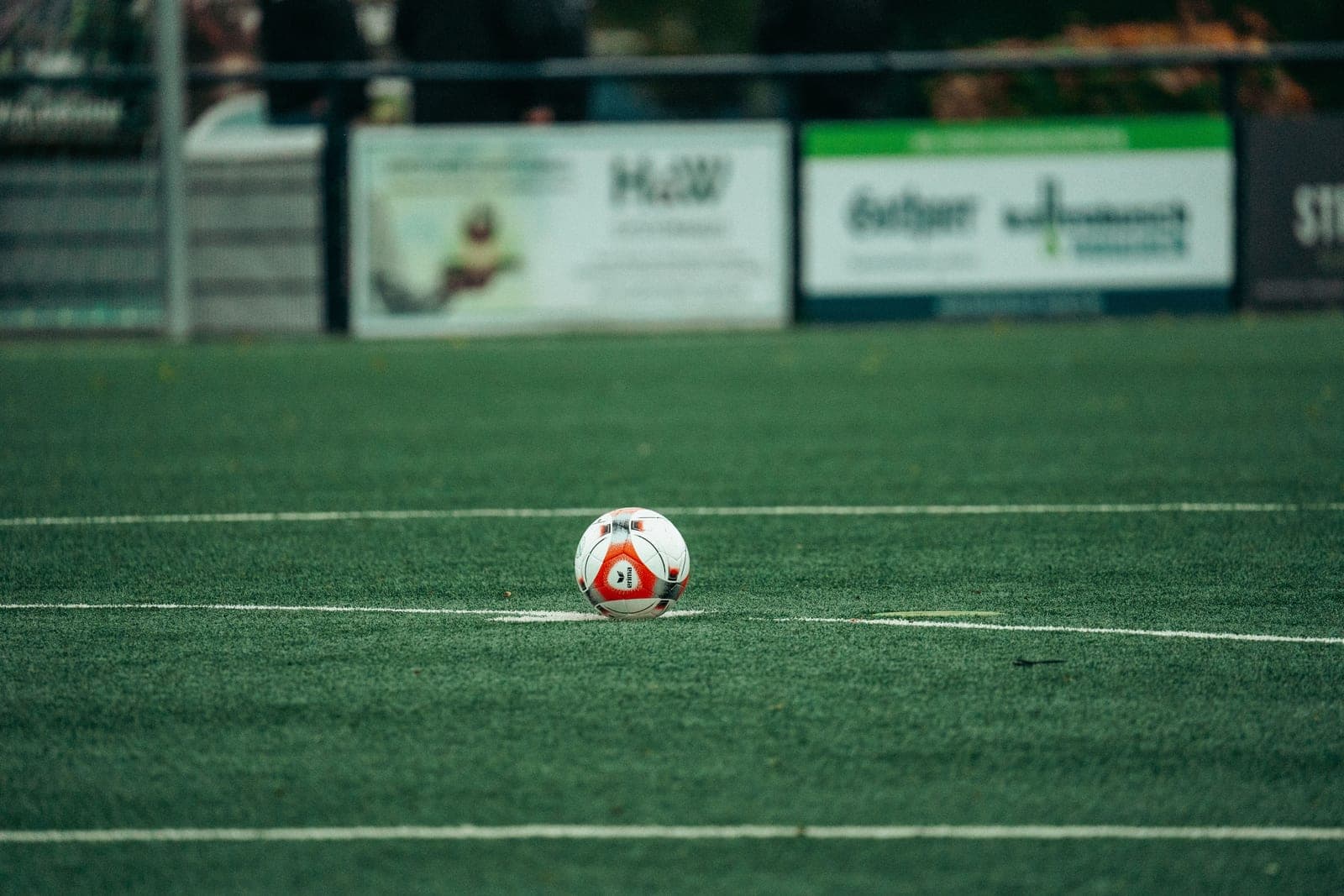 A white soccer ball on a grass pitch