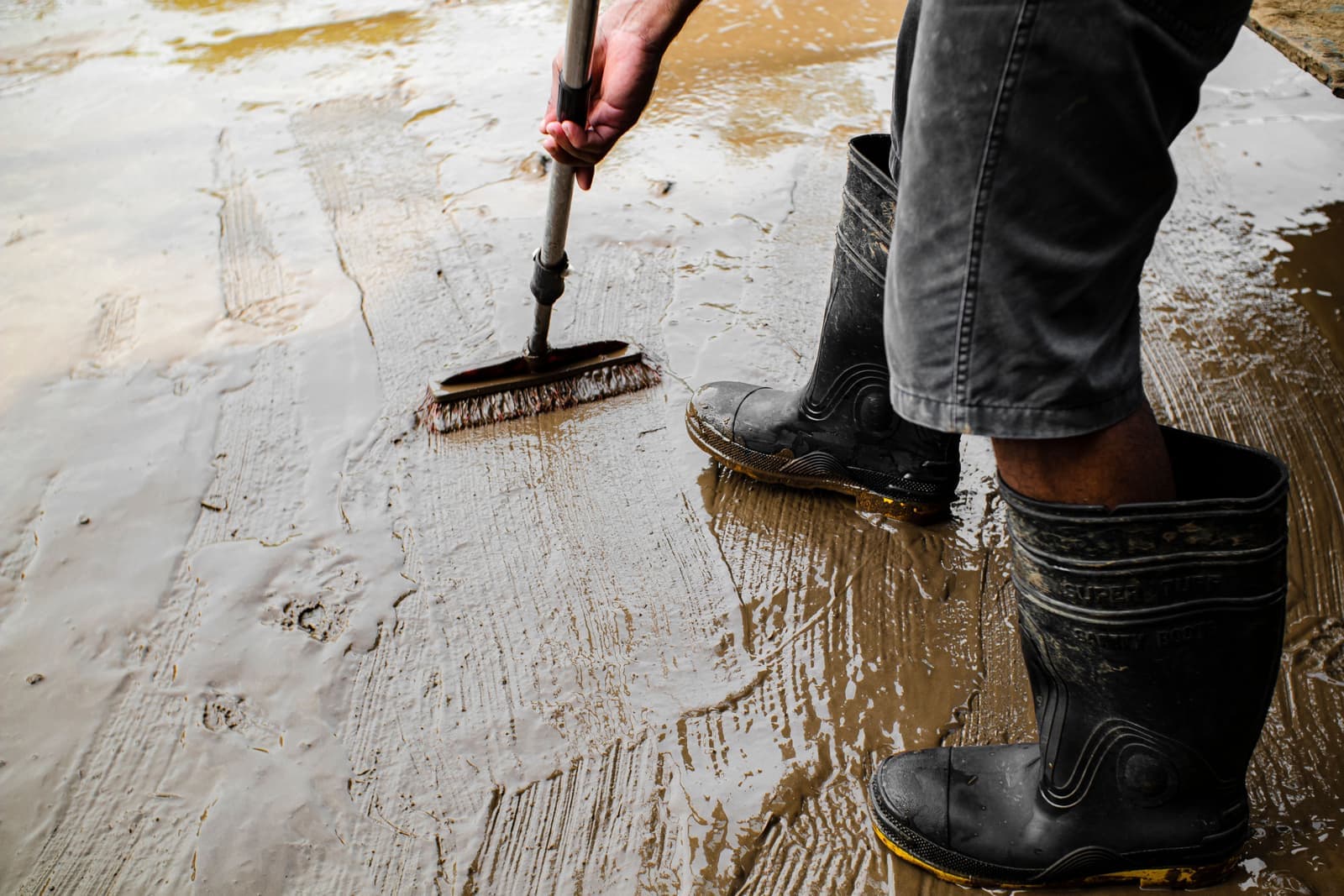 Muddy soccer boots being cleaned with a brush