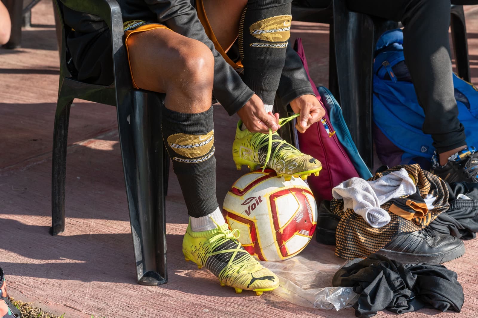 A child fastening the laces on a soccer cleat