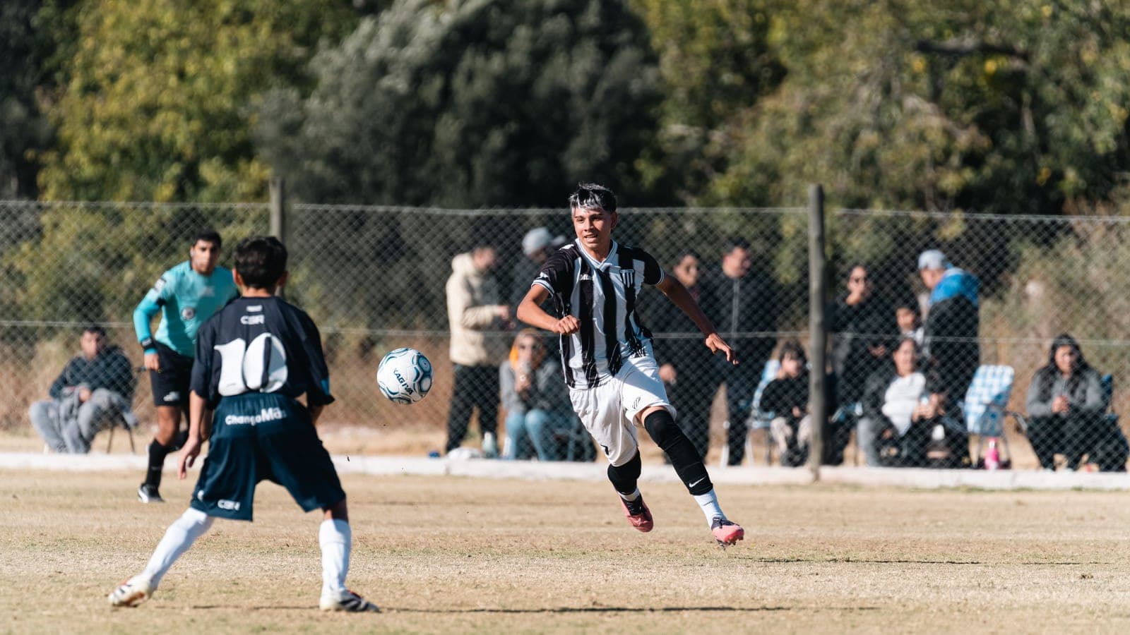 A young soccer player dribbling a ball across a grass field