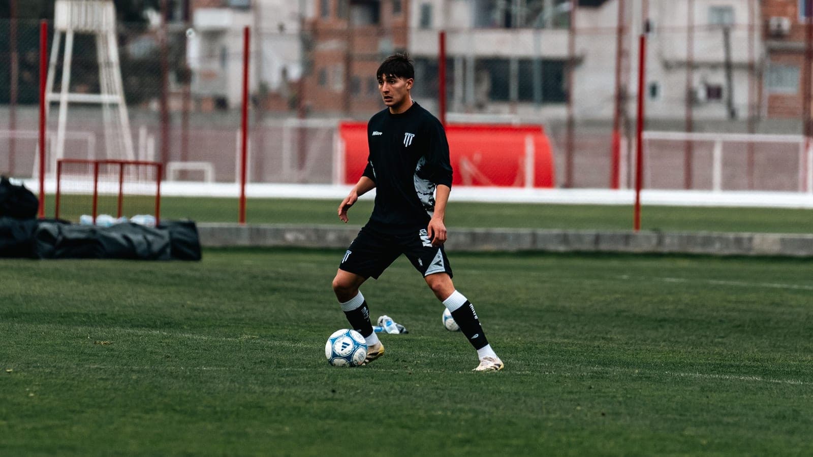 A teenage soccer player training on a full-size pitch
