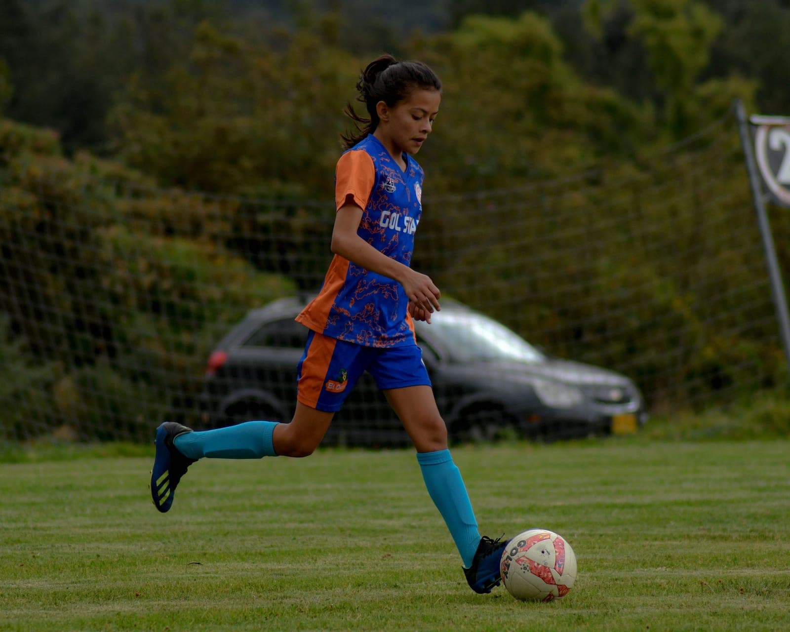 A young child running with a soccer ball on a grass field