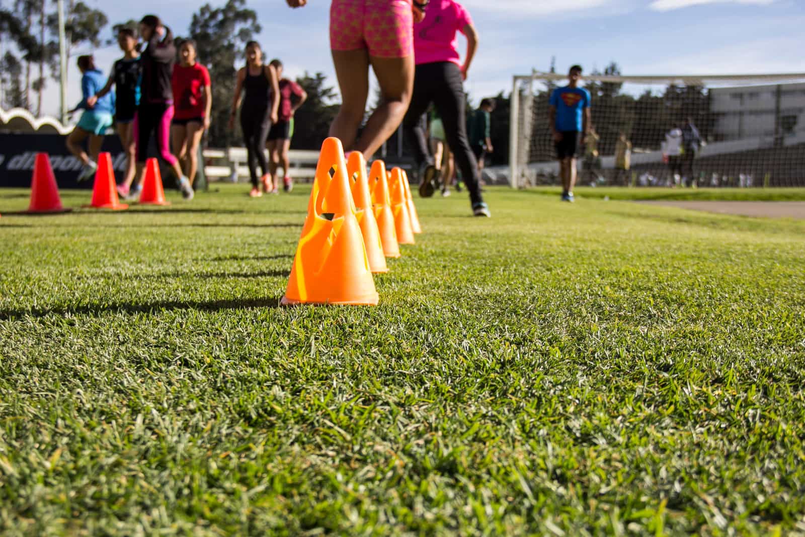 Children at a youth soccer practice, working through a drill between cones