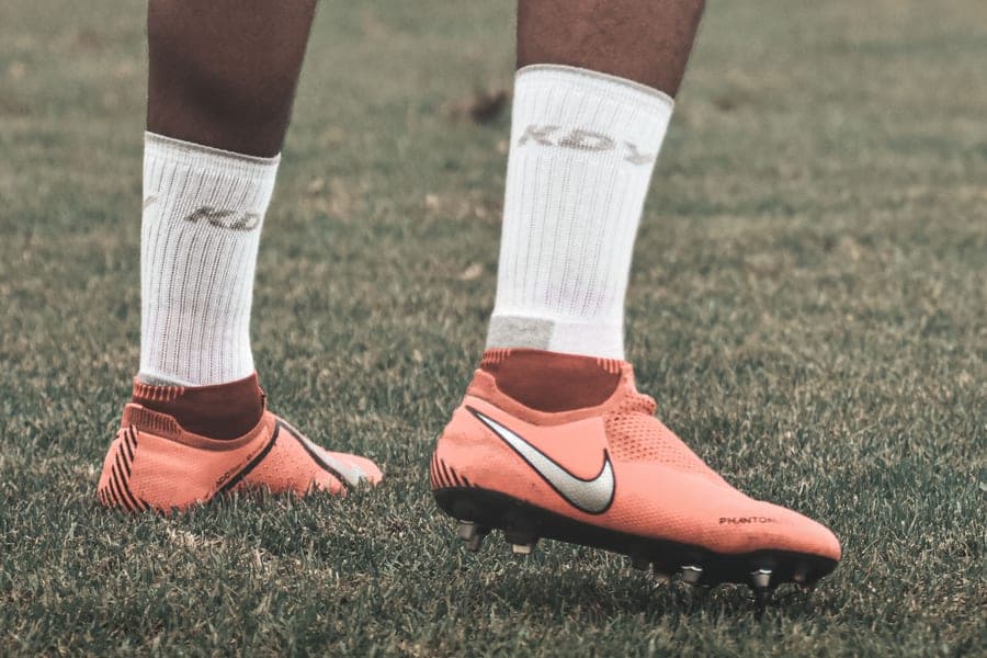 A pair of youth firm-ground soccer cleats photographed on a plain surface